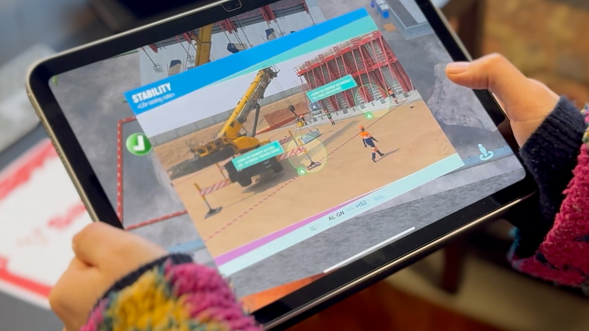 Interactive construction safety training on an iPad, showing hazard awareness guidance and safety scenarios on a virtual construction site.