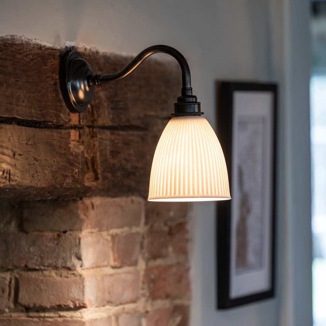 Hartlip Ribbed Ceramic Shade Wall Light mounted on a rustic brick fireplace