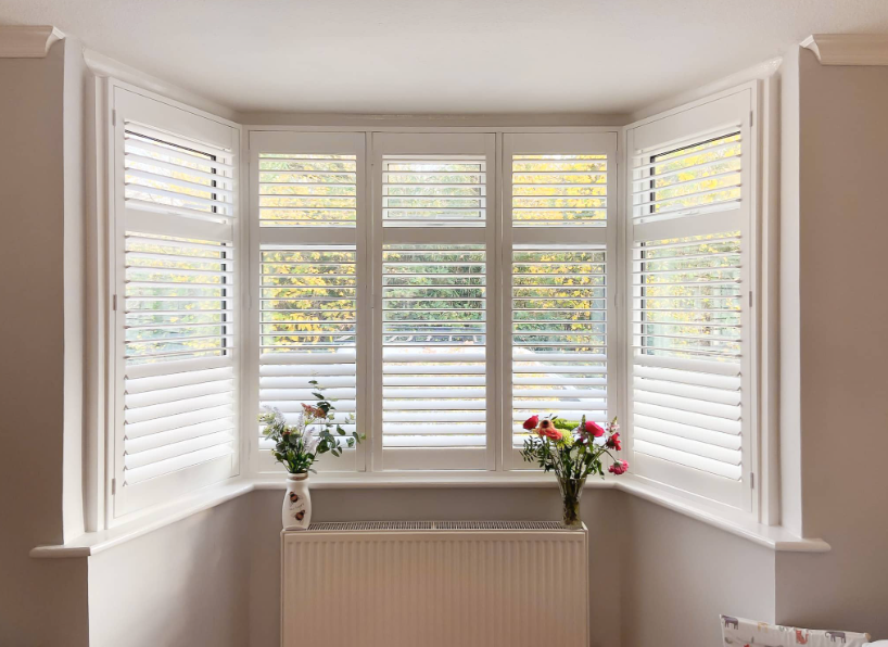 Full height UK made white plantation shutters in a lounge