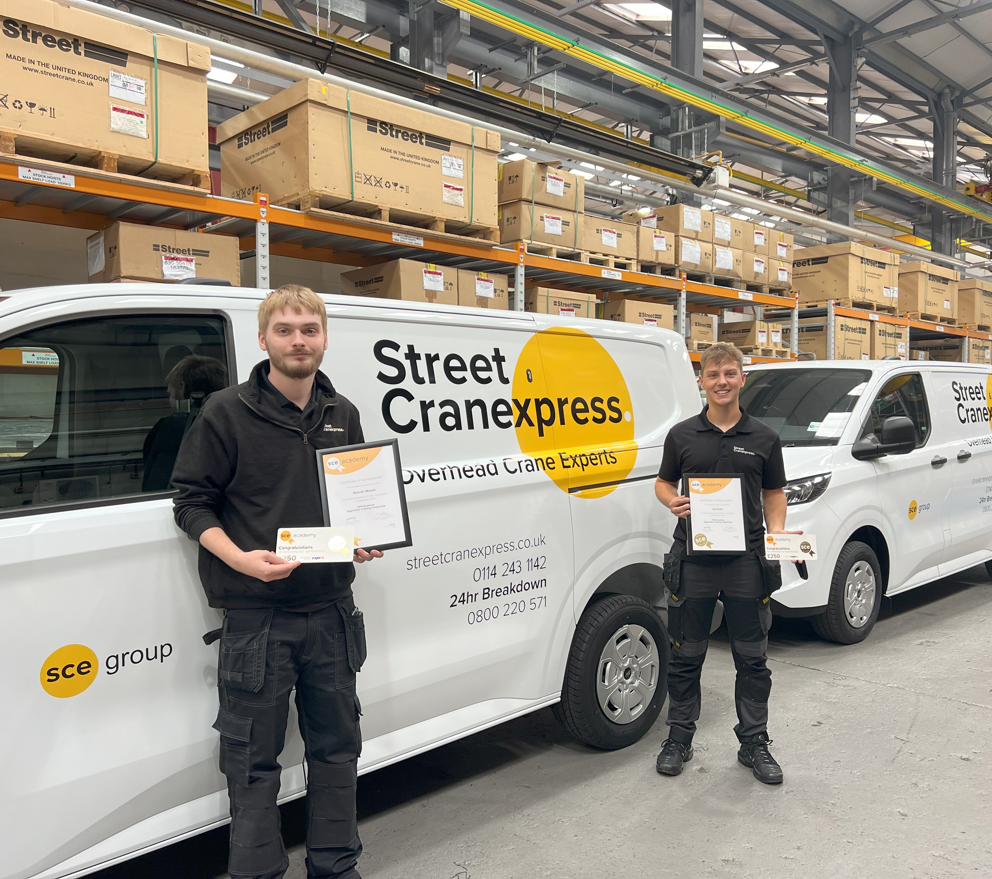 The image shows Jay and Deacon, two Street Cranexpress apprentice engineers collecting their certificates at Street Cranexpress HQ in Sheffield