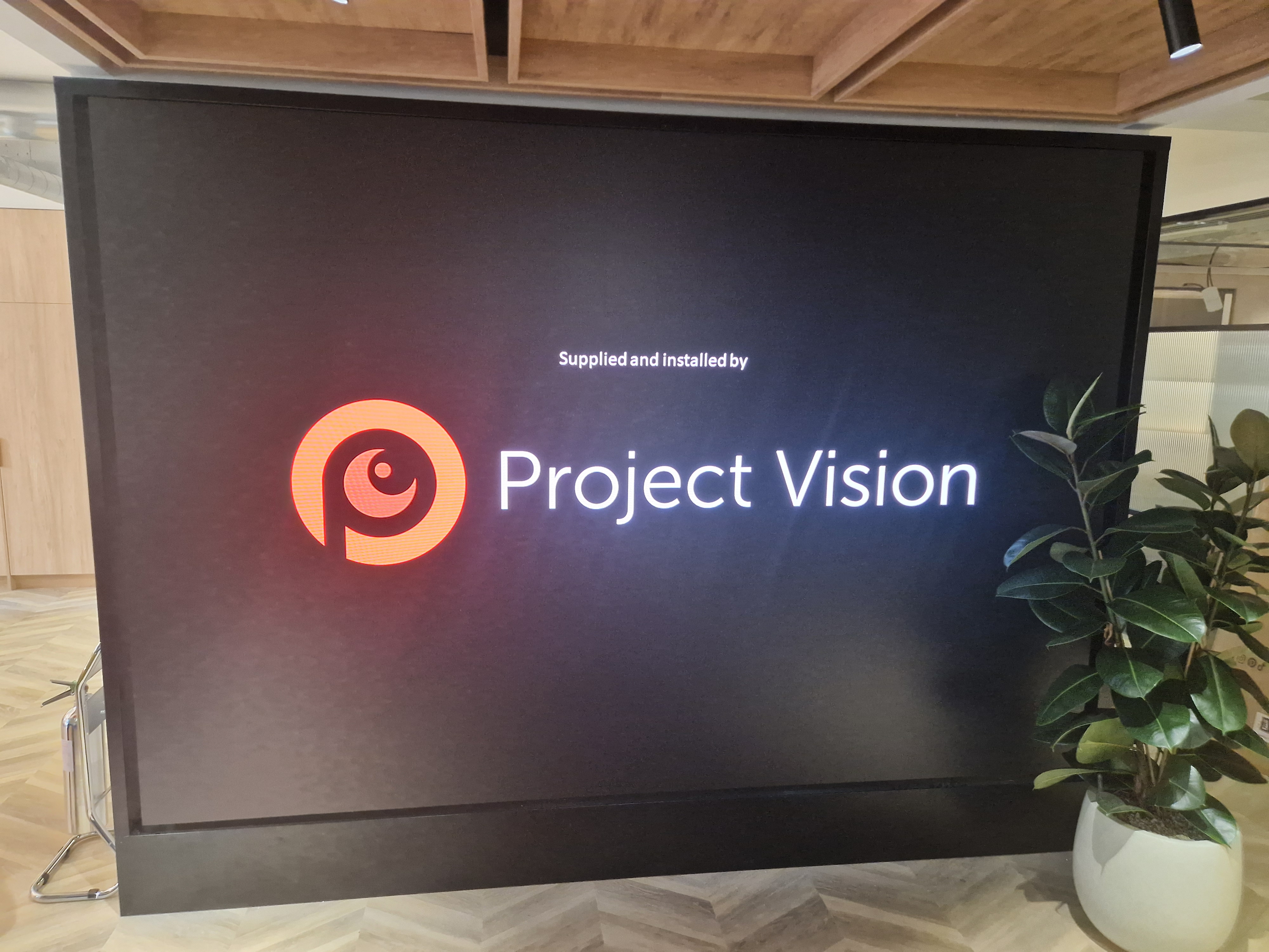 Commercial video wall installation by Project Vision displaying company branding in a modern office environment.
