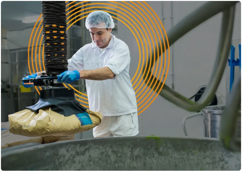 Food production worker operating a vacuum lifter to lift bags in a preparation area
