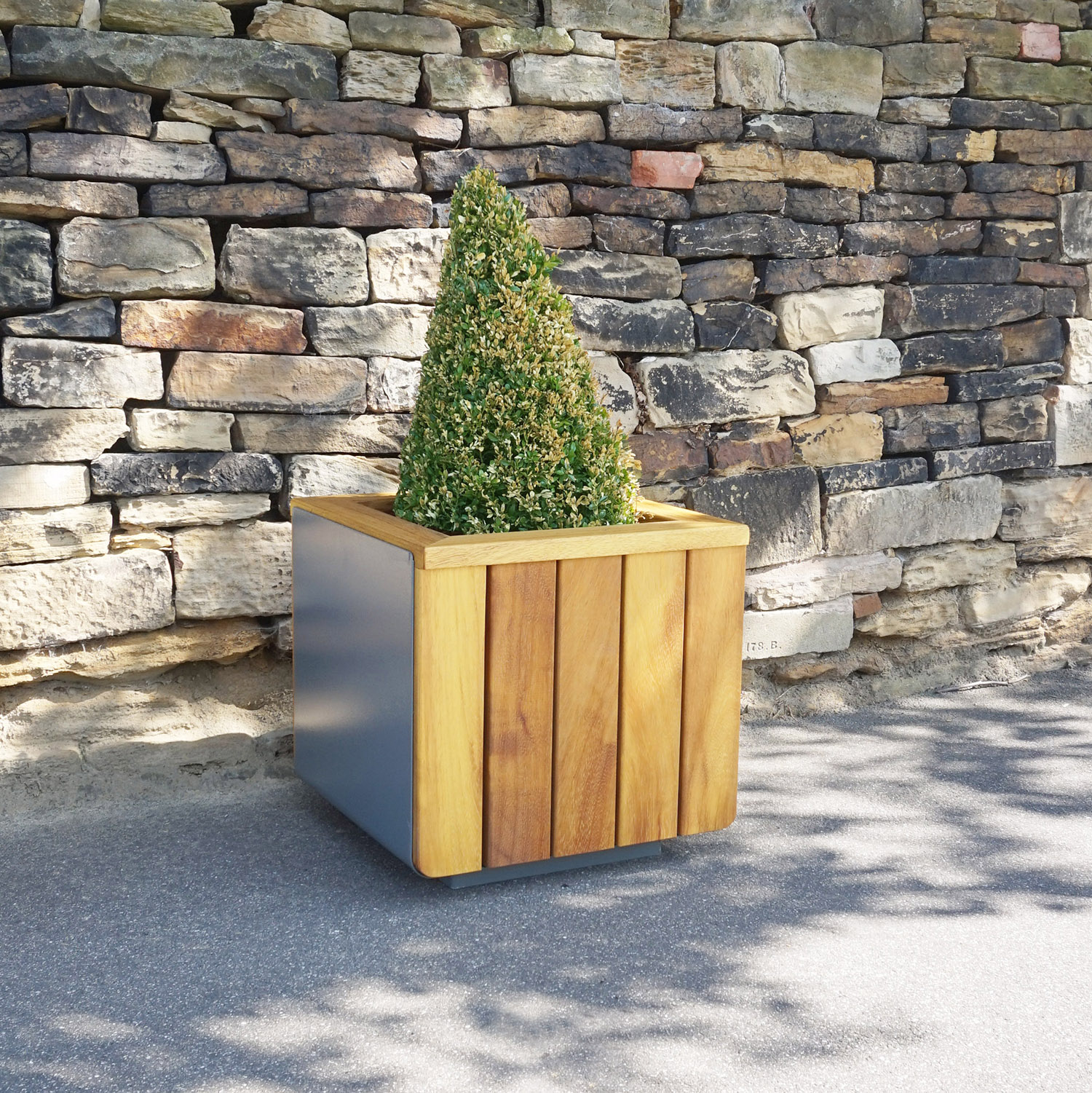 Wooden Paneled, Steel body Contour Flower Planter against stone wall.