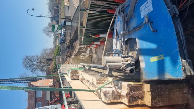 Wall held up by straps attached to crane as isolating cuts completed