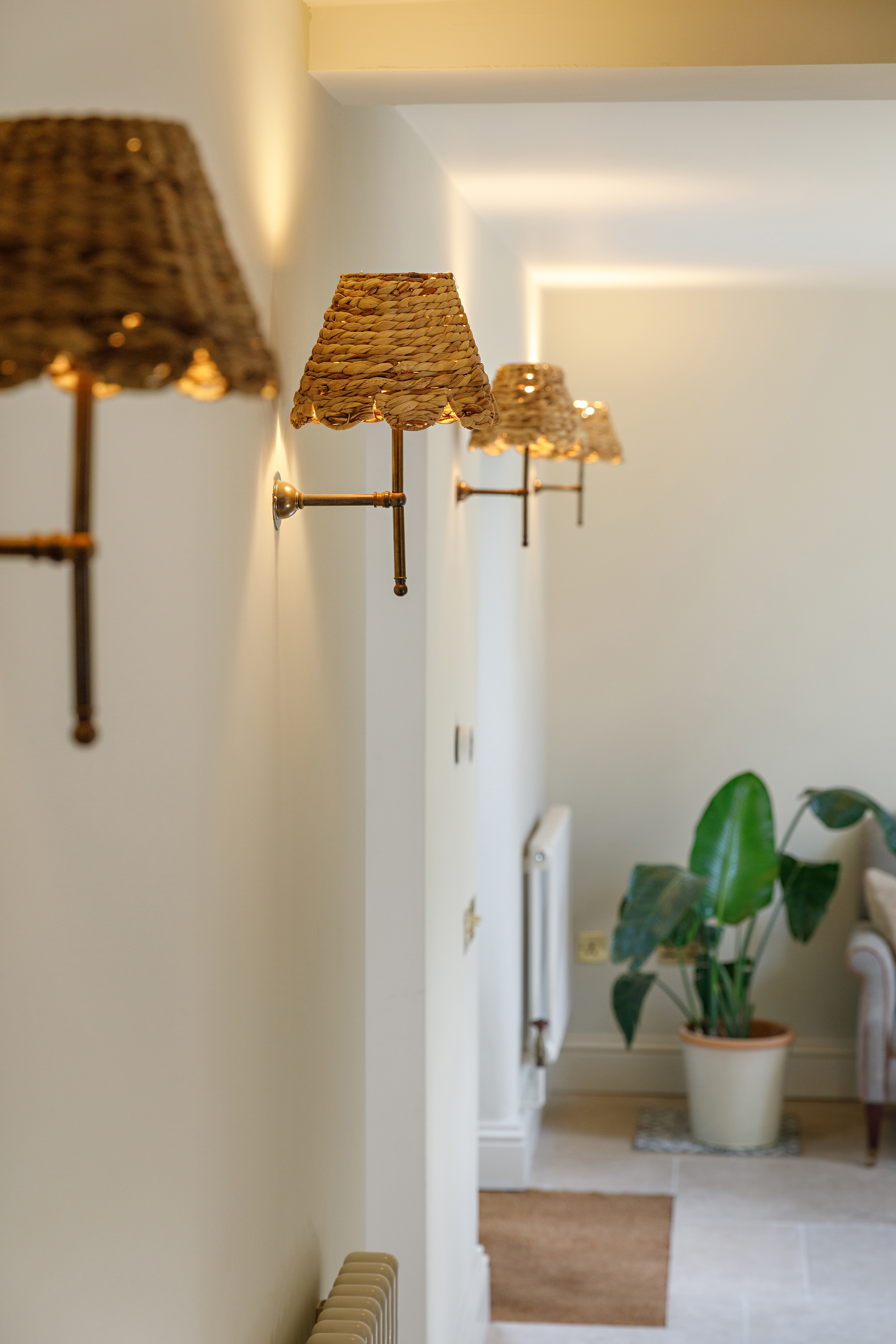four seagrass shades on a lupin antique brass fitting lining a hallway