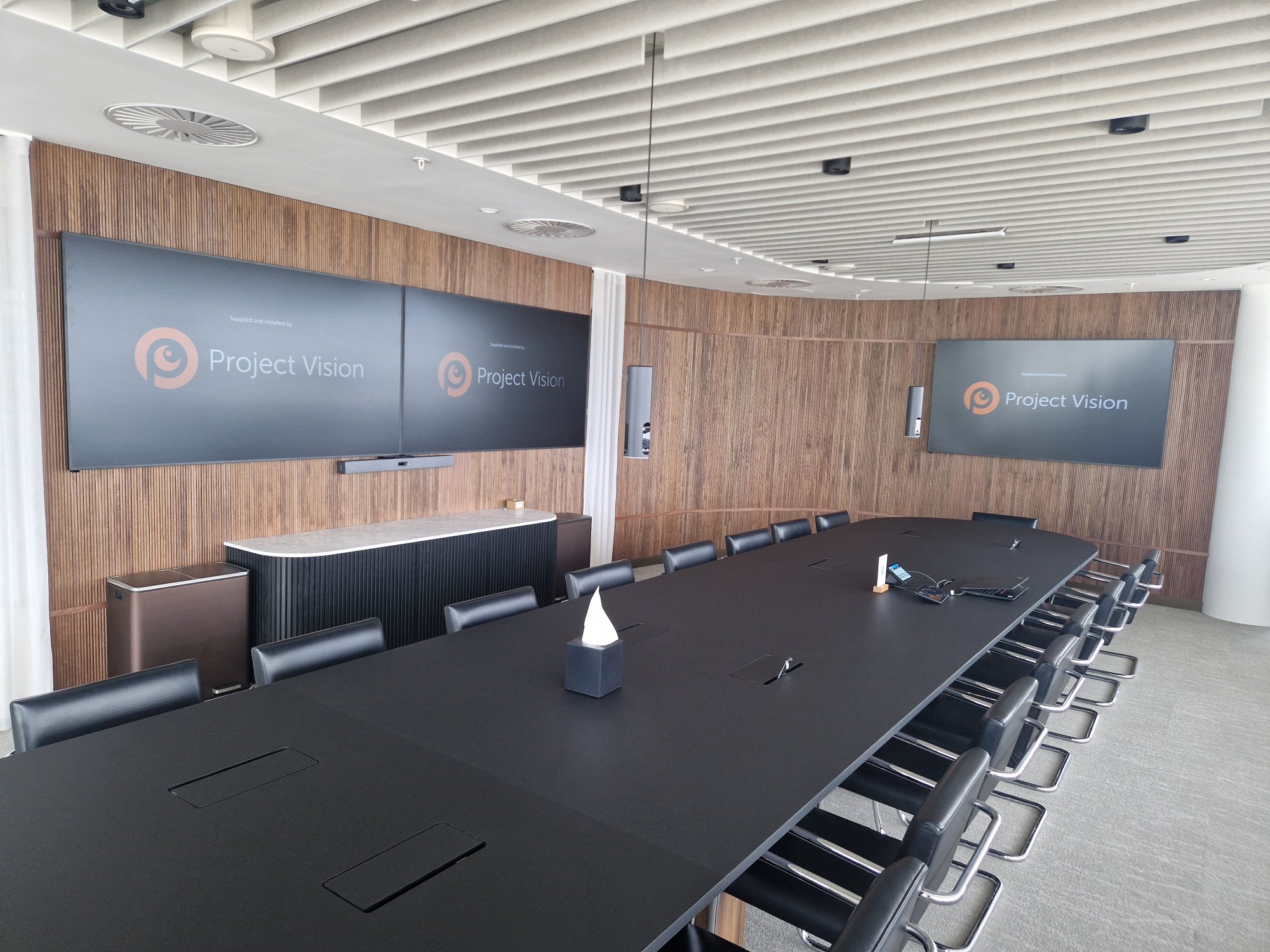 Modern corporate boardroom with large dual-screen video wall, additional display and integrated video conferencing technology installed by Project Vision.