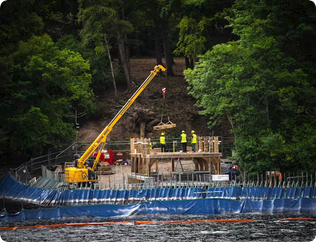Timber being lifted and positioned on a coastal construction site to erect a timber frame.