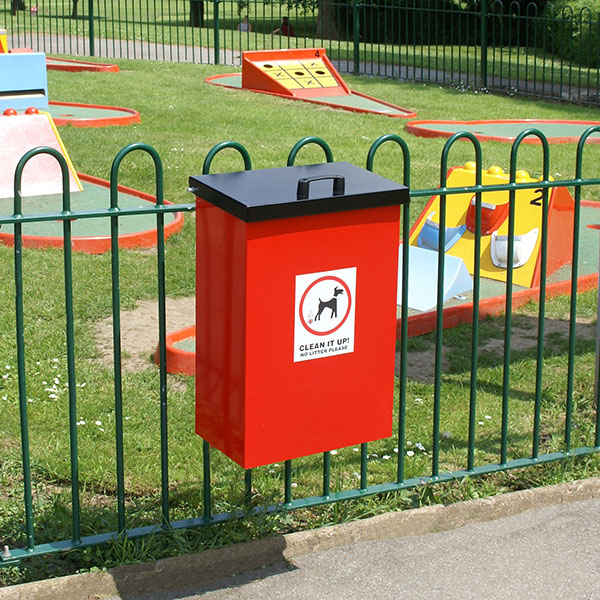Red Dog Waste Bin with Lift Up Lid on a park fencing
