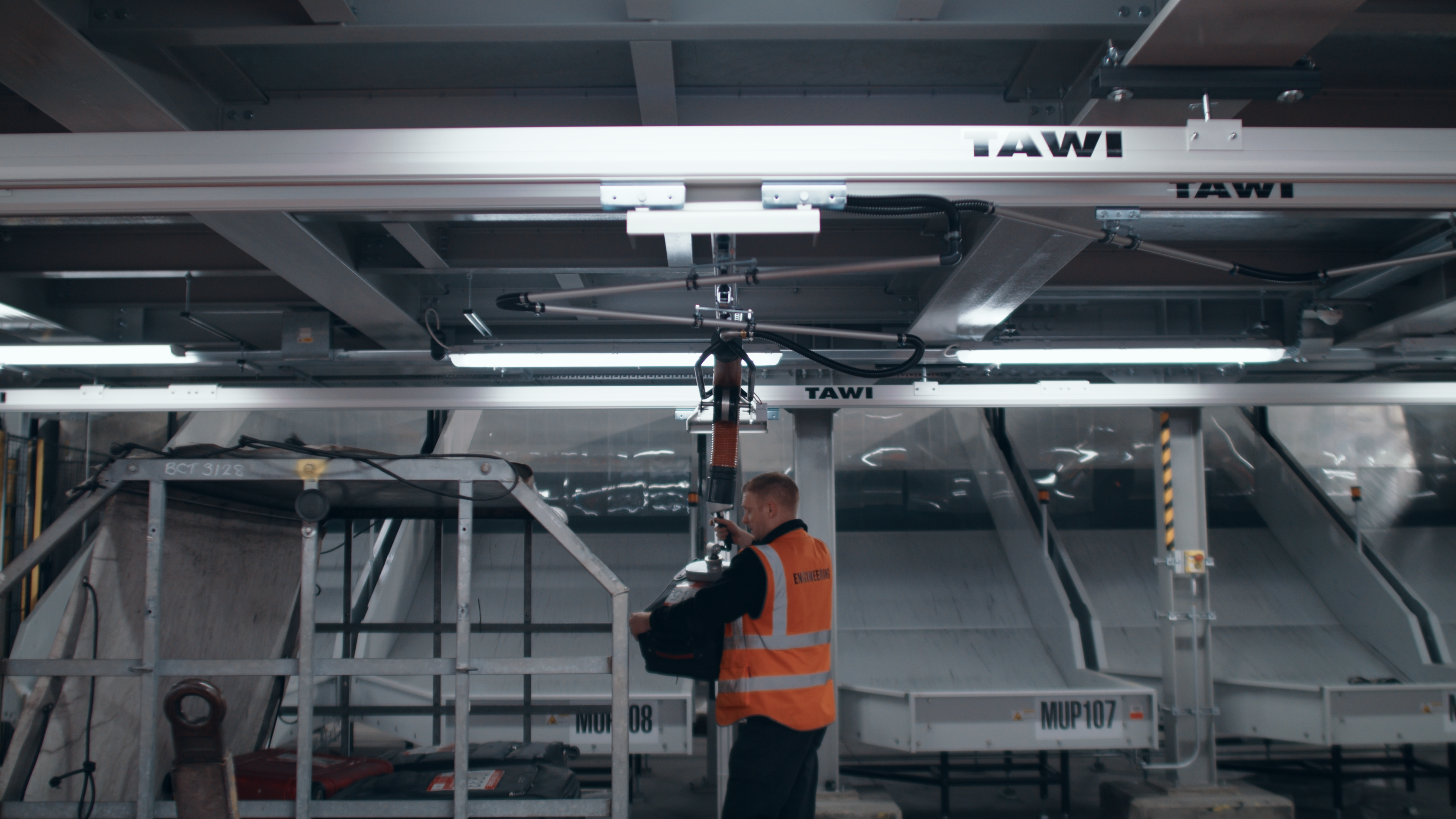 Stansted Airport baggage handler using a TAWI vacuum lifter to move luggage onto a dolly